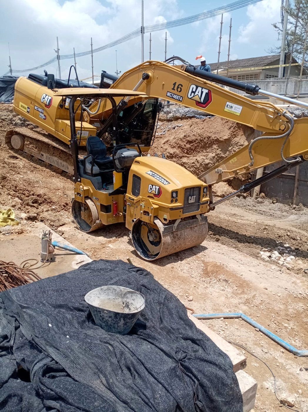 Retroexcavadora y compactador en obra